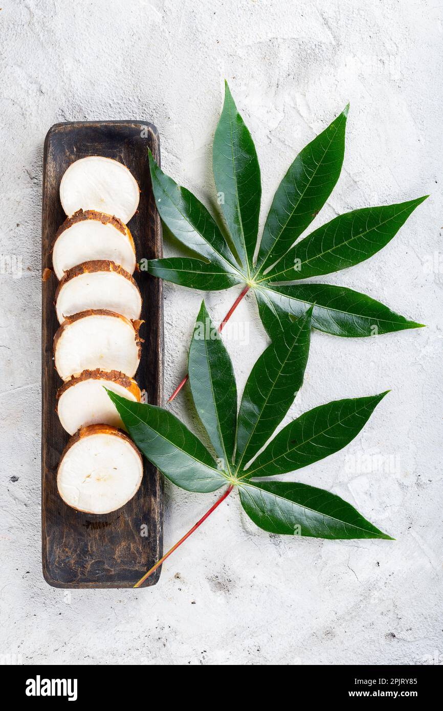 Tranches de manioc dans un récipient en bois, sur fond blanc Banque D'Images