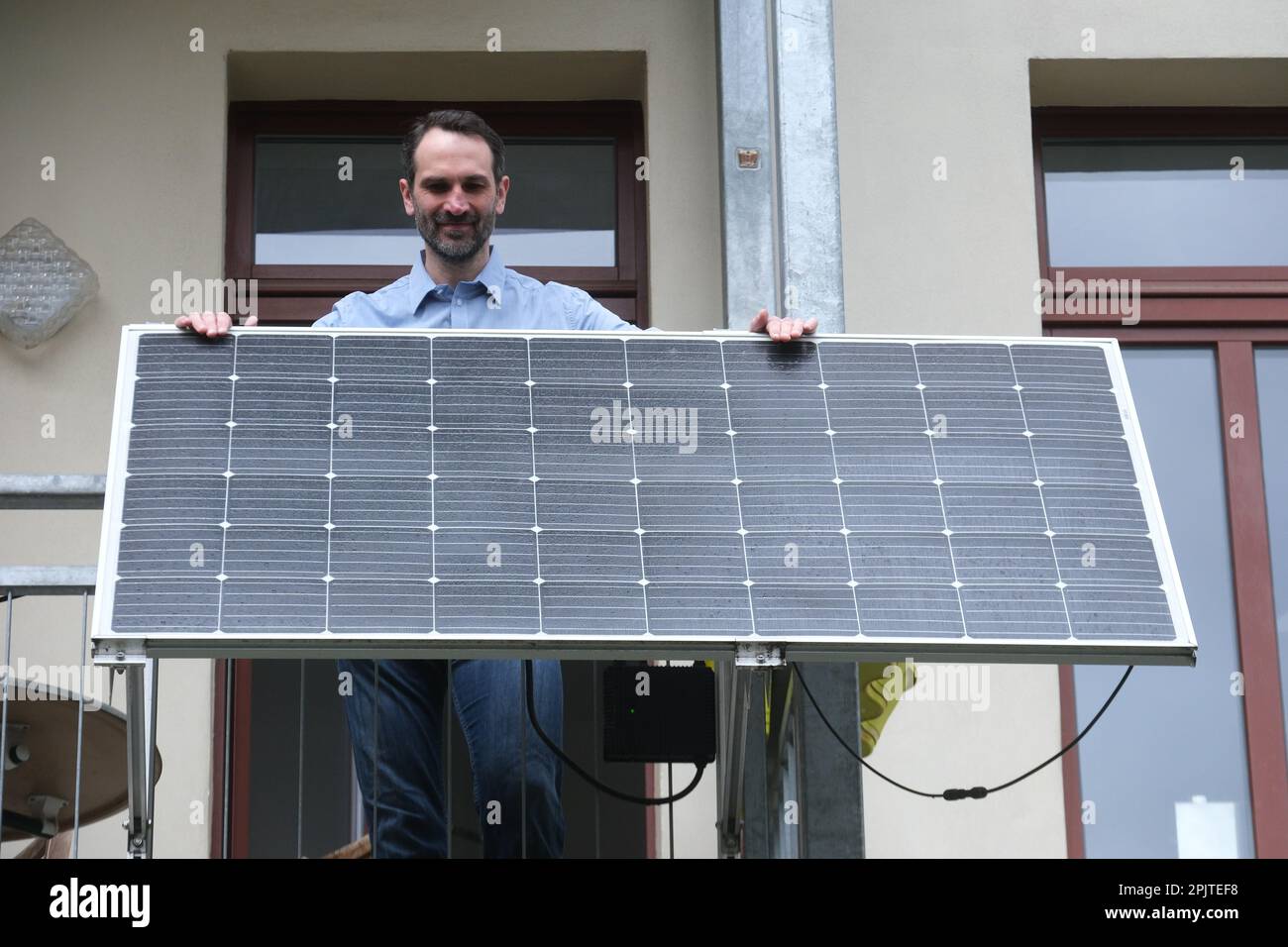 Leipzig, Allemagne. 30th mars 2023. Un homme se tient sur le balcon de son appartement derrière un module solaire fabriqué par la société Priwatt de Leipzig. La société fabrique ce que l'on appelle des centrales électriques de balcon pour les appartements. (À dpa: «Boom dans les systèmes solaires - la mini centrale électrique pour le balcon») Credit: Sebastian Willnow/dpa/Alamy Live News Banque D'Images