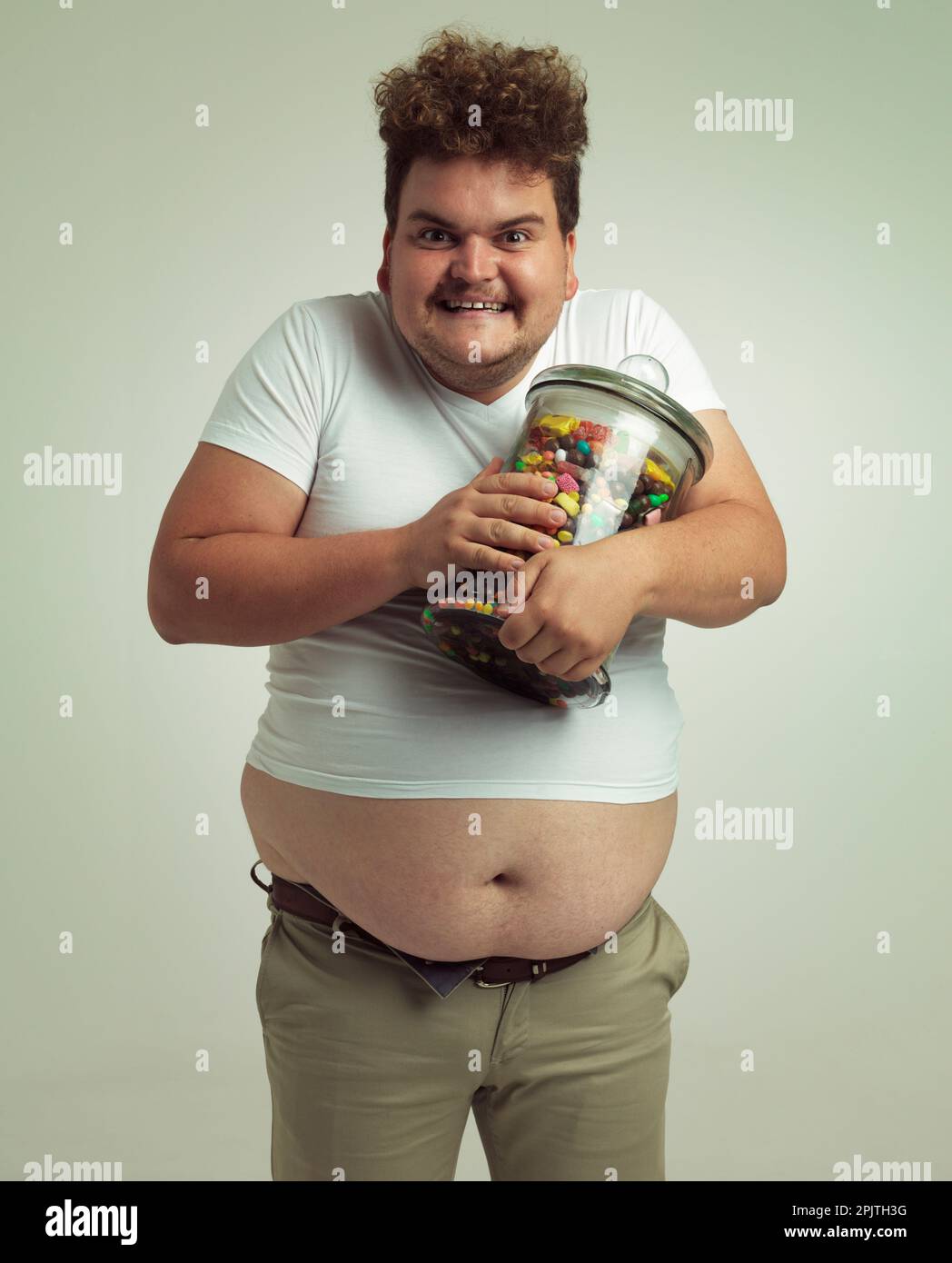 Il est temps de faire une ruée vers le sucre. un homme en surpoids tenant un grand pot de bonbons. Banque D'Images