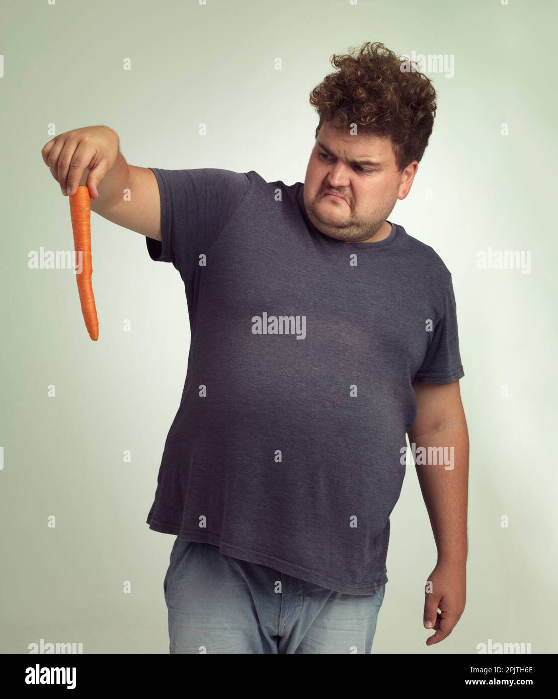 Qu'est-ce que ce bâton orange ? un homme en surpoids tenant une carotte. Banque D'Images
