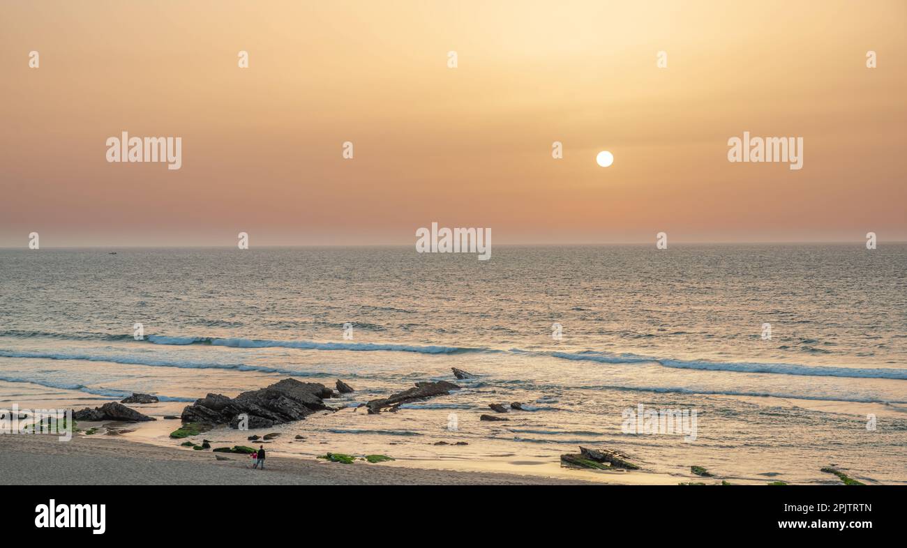 Les enfants regardent un magnifique coucher de soleil sur la rive sablonneuse de l'océan Atlantique. Banque D'Images
