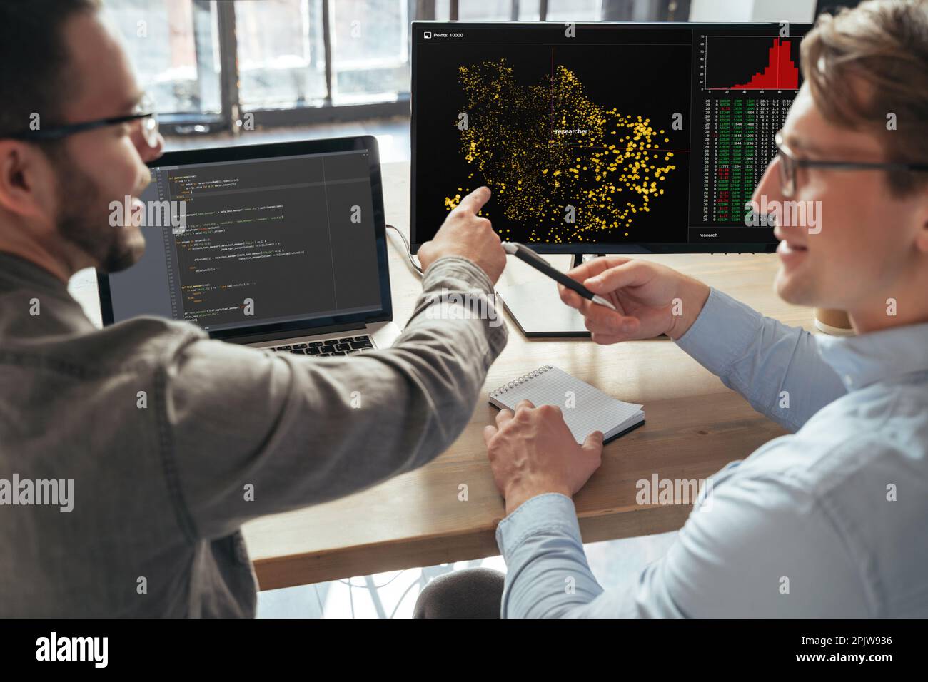 Gros plan de deux spécialistes de l'apprentissage automatique qui se désintent du nouveau projet au bureau, devant un pc, en analysant les données. Mise au point sélective sur l'écran de l'ordinateur Banque D'Images