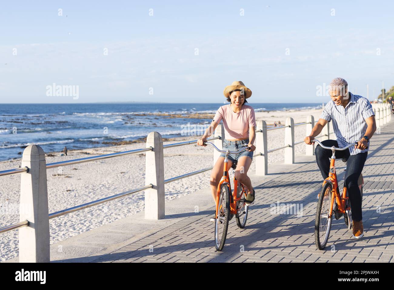 Heureux couple divers à vélo le long de la promenade au bord de la mer Banque D'Images