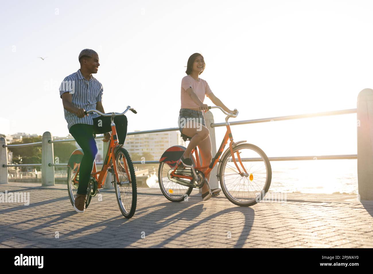 Heureux couple divers à vélo le long de la promenade au bord de la mer Banque D'Images