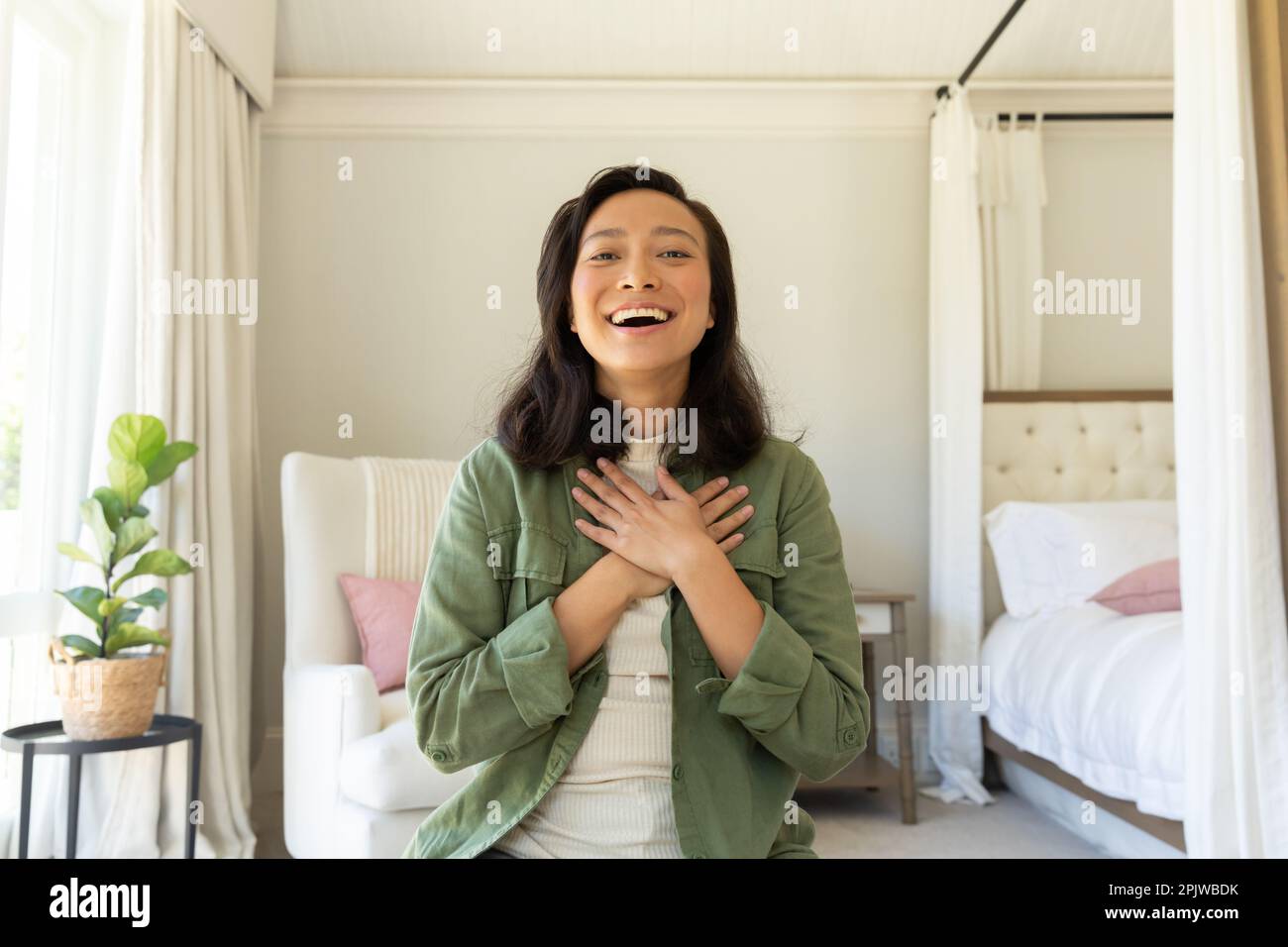 Bonne femme asiatique utilisant avoir un appel vidéo dans la chambre Banque D'Images