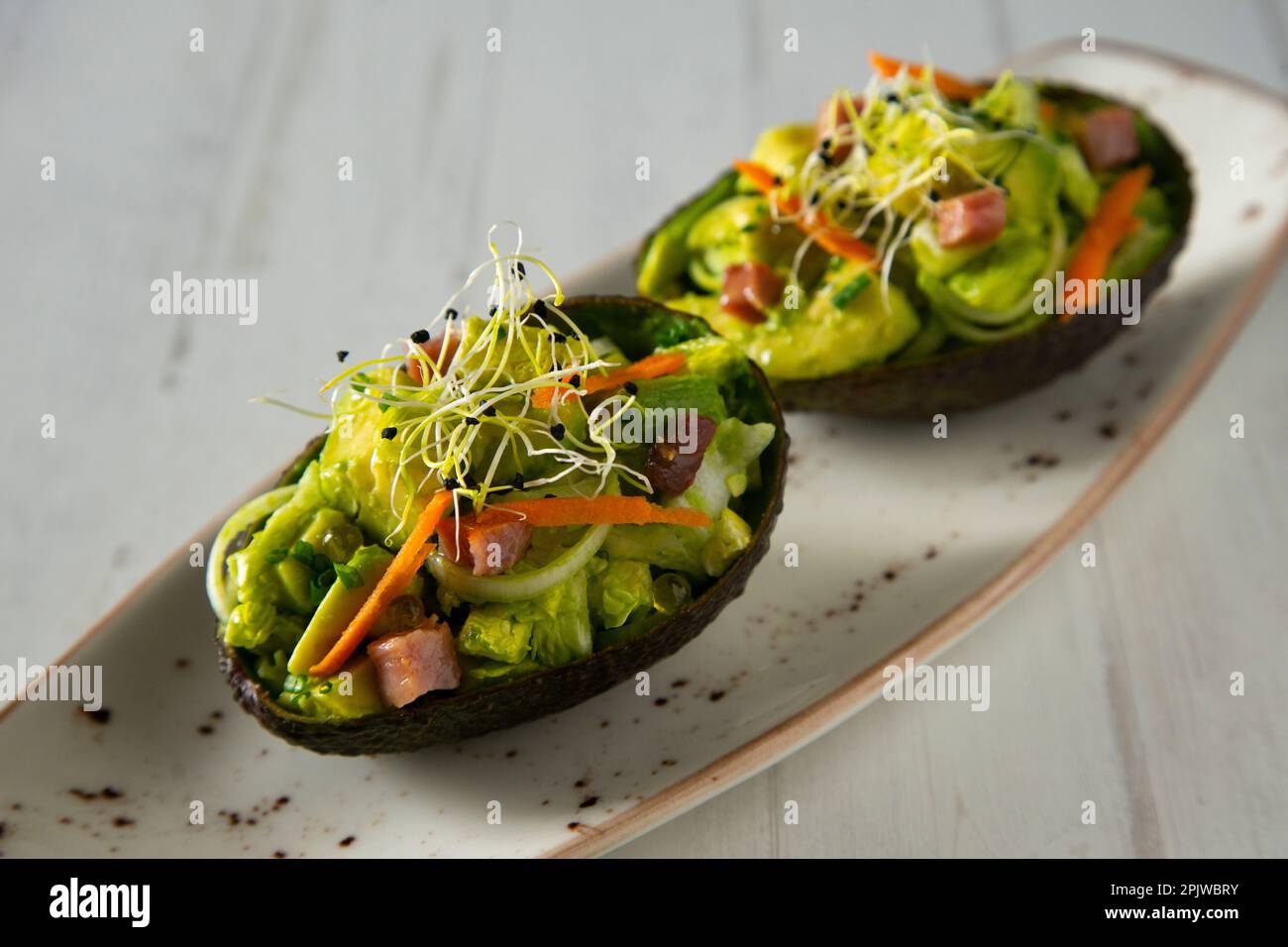 Recette de petit déjeuner avec avocat farci d'oeuf et de jambon. Banque D'Images