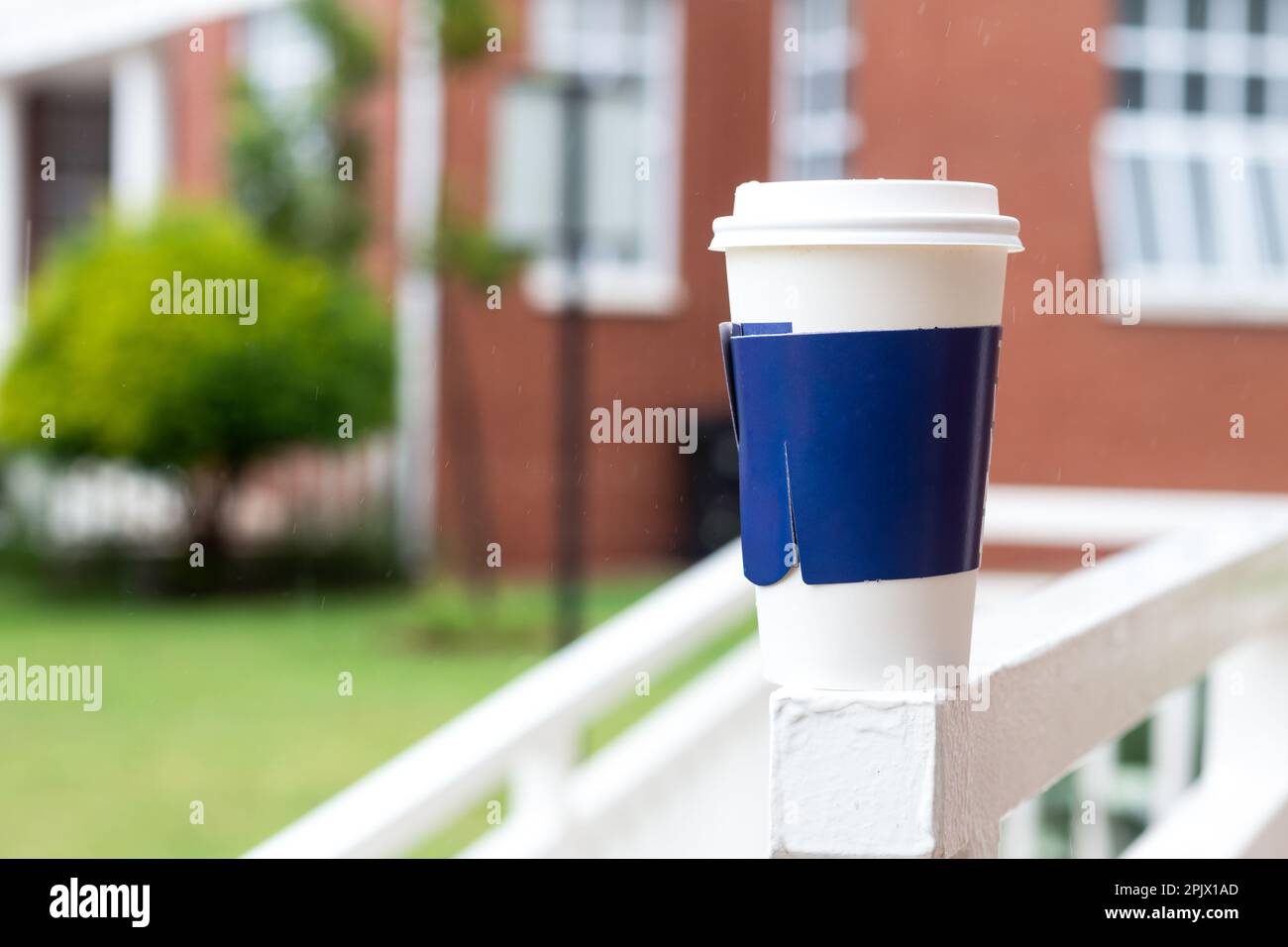 Tasse à café blanche jetable avec manche bleu Banque D'Images