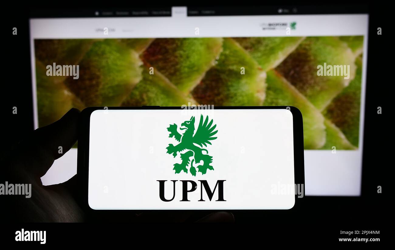 Personne tenant un smartphone avec le logo de la société forestière finlandaise UPM-Kymmene Oyj à l'écran devant le site Web. Mise au point sur l'affichage du téléphone. Banque D'Images