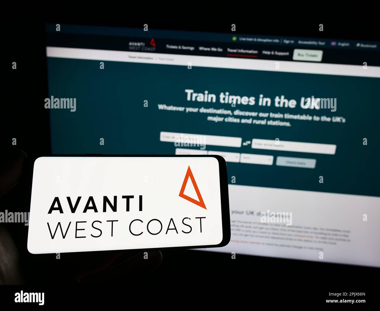 Personne tenant un smartphone avec le logo de la compagnie de train britannique Avanti West Coast sur l'écran devant le site Web. Mise au point sur l'affichage du téléphone. Banque D'Images