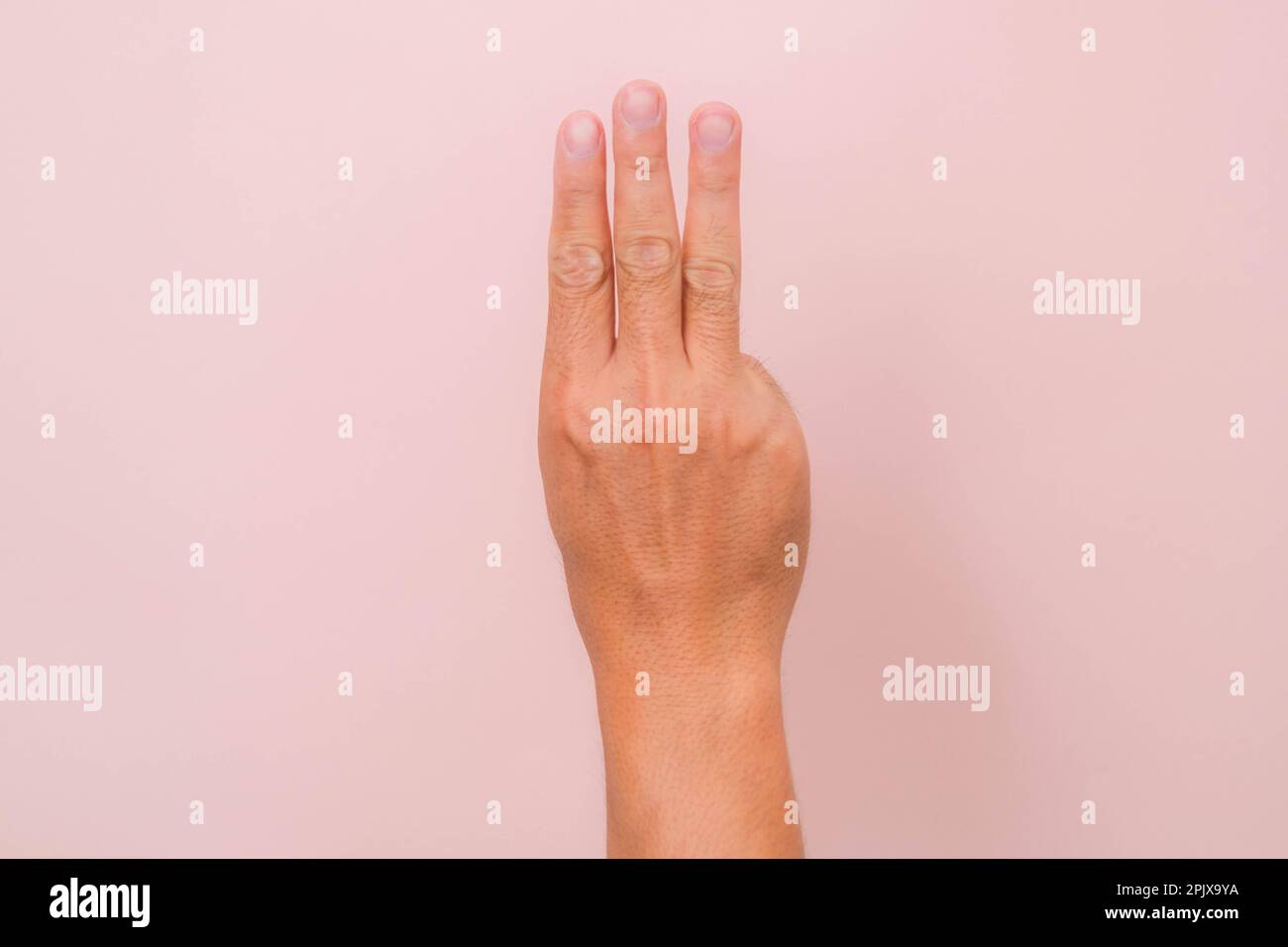 Main masculine montrant trois doigts saluant comme un symbole pour avoir protesté contre le dictateur dans le pays asiatique. Signe de main d'homme isolé sur fond rose Banque D'Images