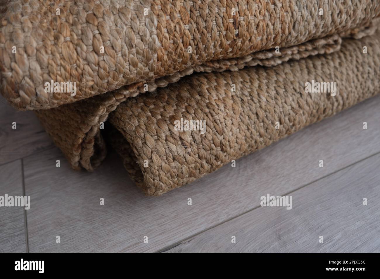 Moquette de jute en osier pliée, moquette de jute en osier tressée naturelle pliée sur le parquet de la chambre. Idée de tapis de jute en osier photo. Banque D'Images