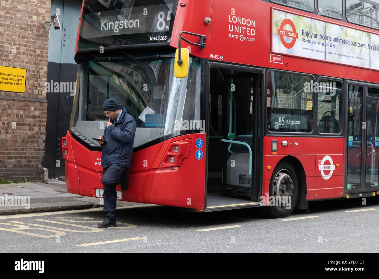 Chauffeur de bus londonien prenant une pause tout en ayant une Vape alors qu'il se penche sur son bus garé à la station Putney Bridge, sud-ouest de Londres, Angleterre, Royaume-Uni Banque D'Images