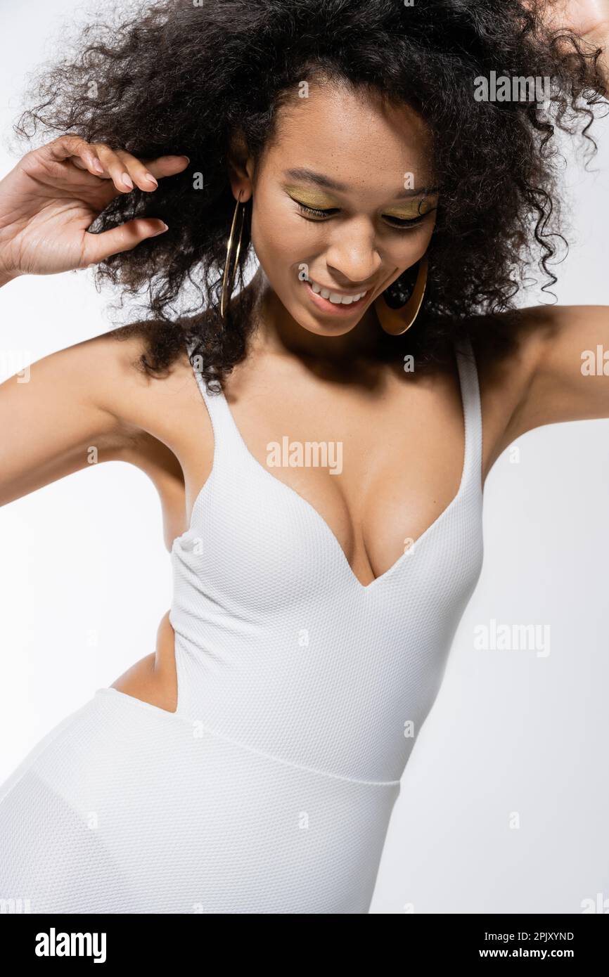 joyeuse femme afro-américaine en robe miniature posant isolée sur le gris Banque D'Images