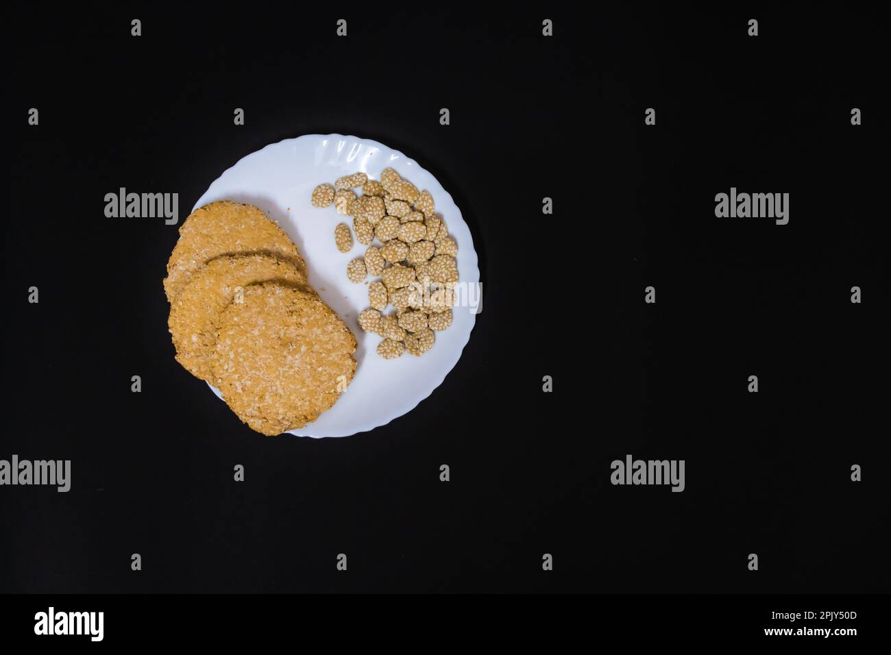 tilkut traditionnel indien sucré dans une assiette blanche avec fond noir Banque D'Images