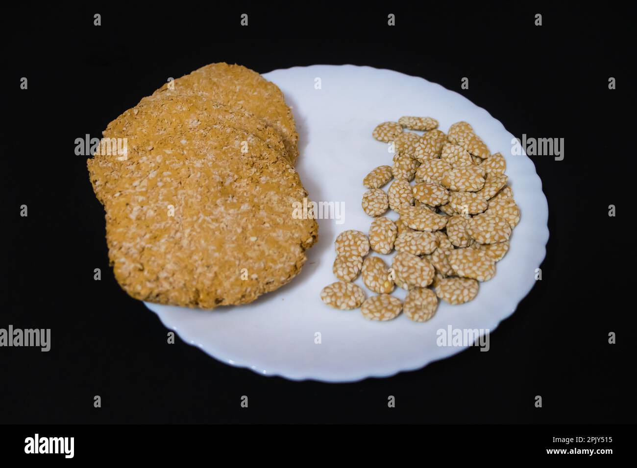 tilkut traditionnel indien sucré dans une assiette blanche avec fond noir Banque D'Images