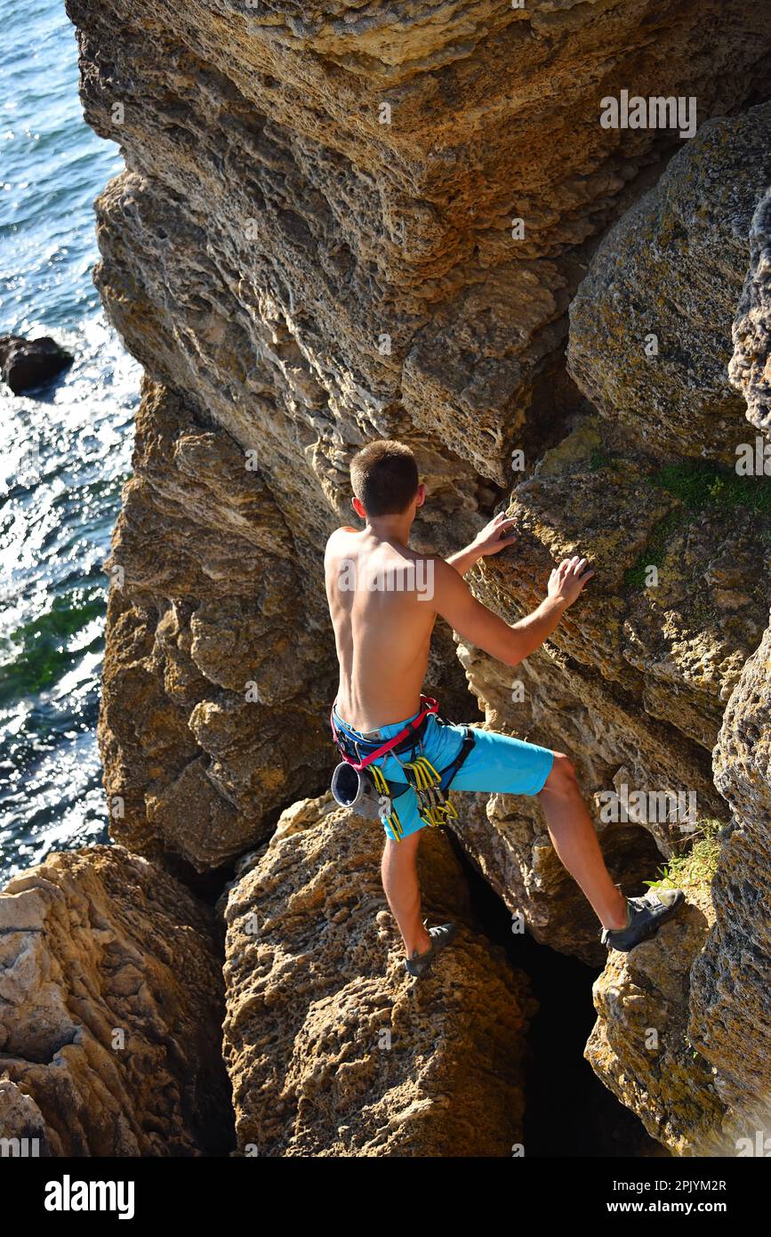 le grimpeur de roche mâle monte sur un mur rocheux, vue d'en haut Banque D'Images