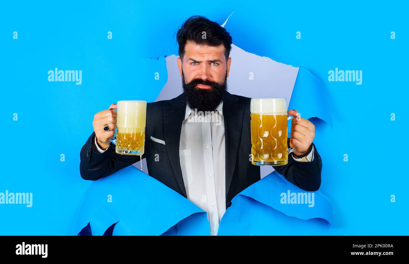 Durée de la bière. Homme barbu avec une tasse de bière artisanale regardant à travers le trou de papier. Publicité au bar ou dans un pub. Alcool. Bière artisanale en Allemagne. Homme d'affaires en costume Banque D'Images