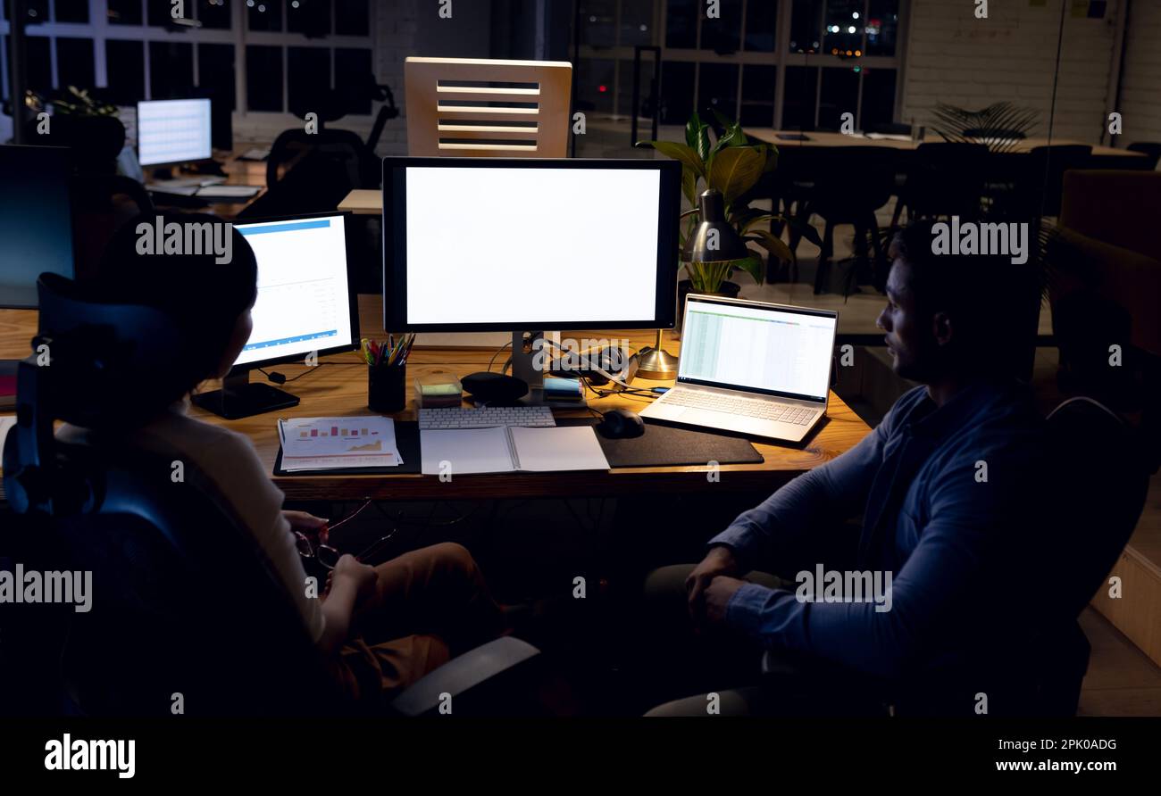 Divers employés d'affaires au bureau, utilisant des ordinateurs avec espace de copie sur les écrans, travaillant tard au bureau Banque D'Images