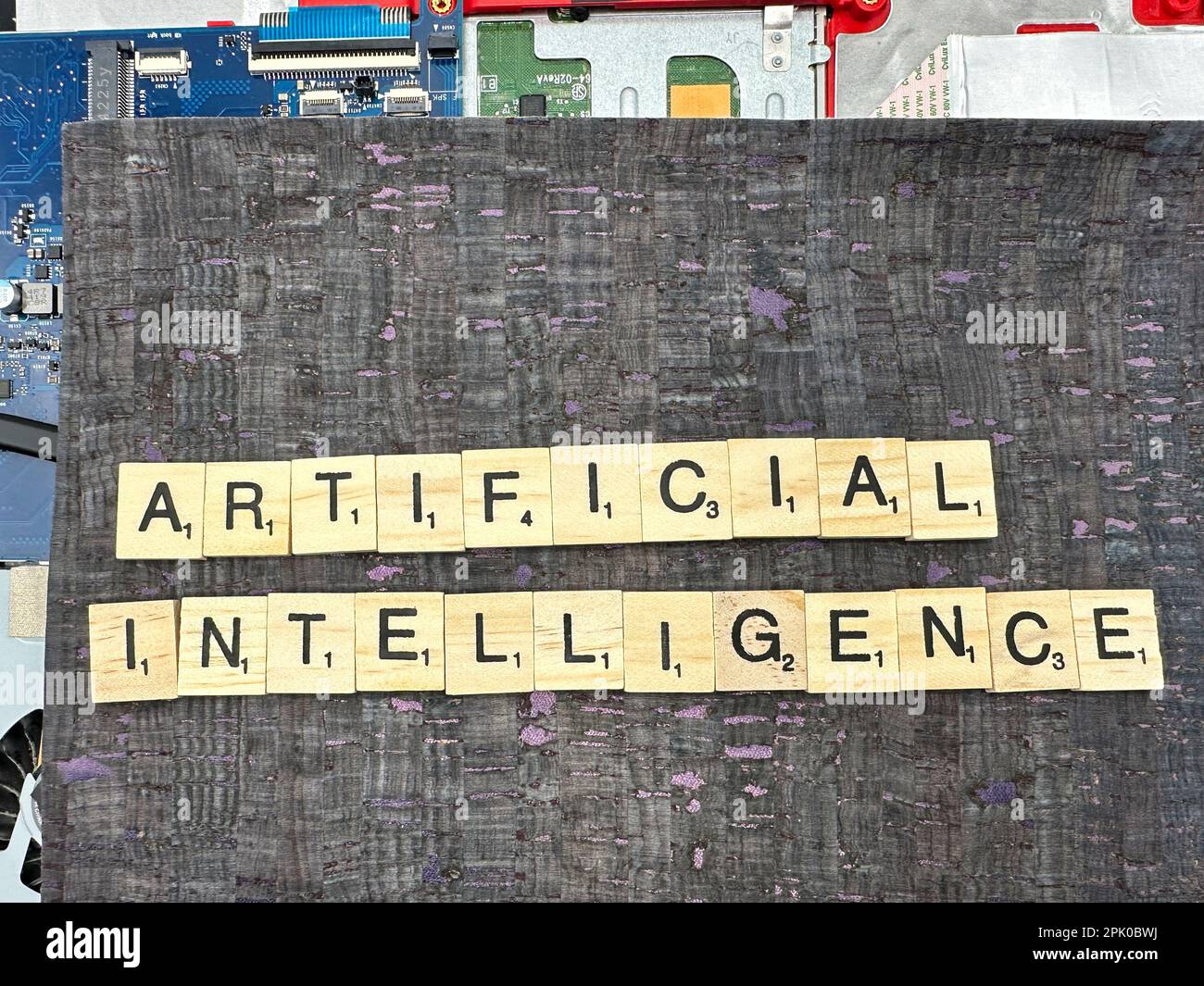 Le mot Intelligence artificielle écrit dans des pièces de jeu de lettres sur une carte mère d'ordinateur avec arrière-plan en cuir fuax Banque D'Images