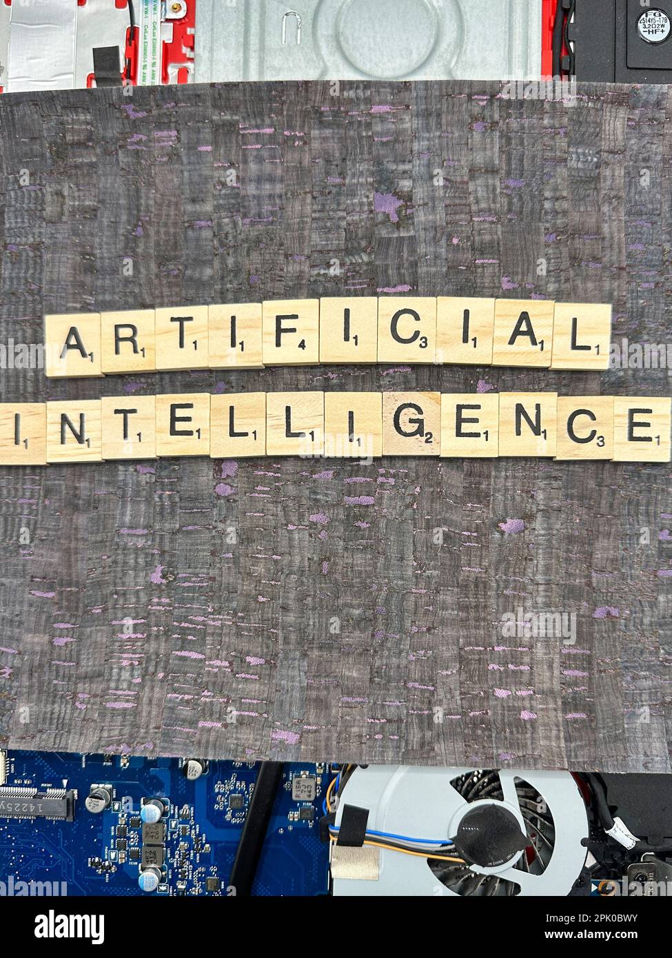 Le mot Intelligence artificielle écrit dans des pièces de jeu de lettres sur une carte mère d'ordinateur avec arrière-plan en cuir fuax Banque D'Images