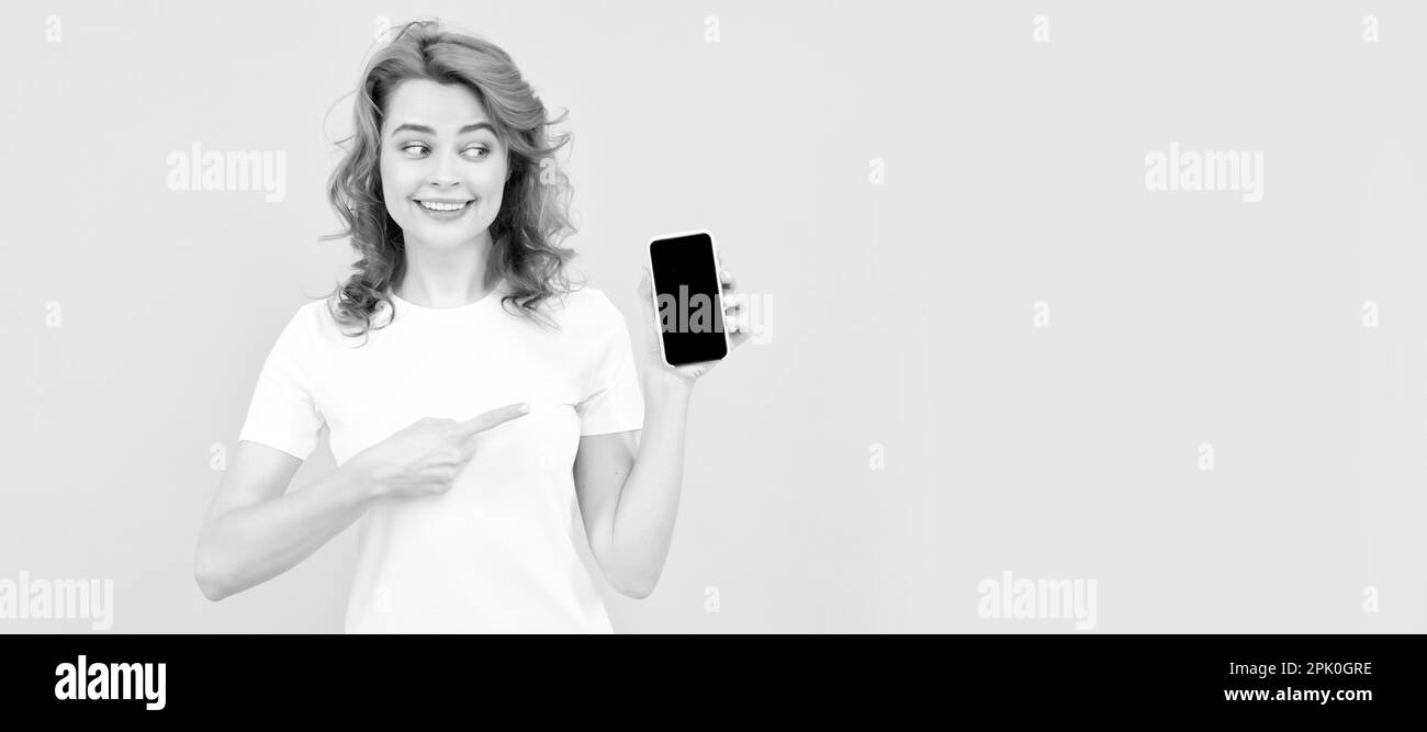 Femme isolée visage portrait, bannière avec espace de copie de maquette. Jeune femme excitée isolé sur fond jaune à l'aide d'un téléphone mobile montrant le geste ok Banque D'Images