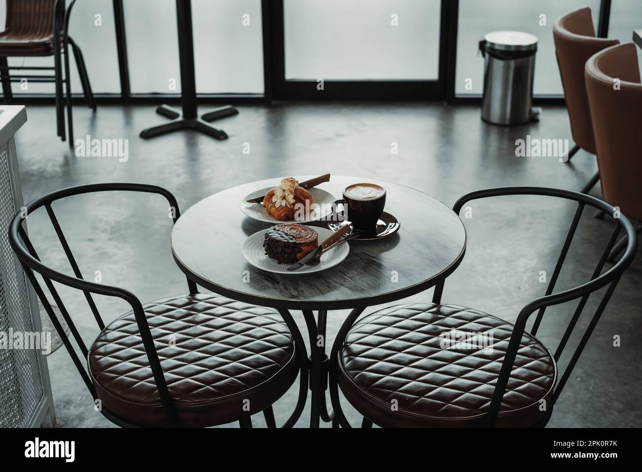 Table à café contient le menu du petit déjeuner : croissant aux amandes, Crombolomi au chocolat et café sur un café Banque D'Images