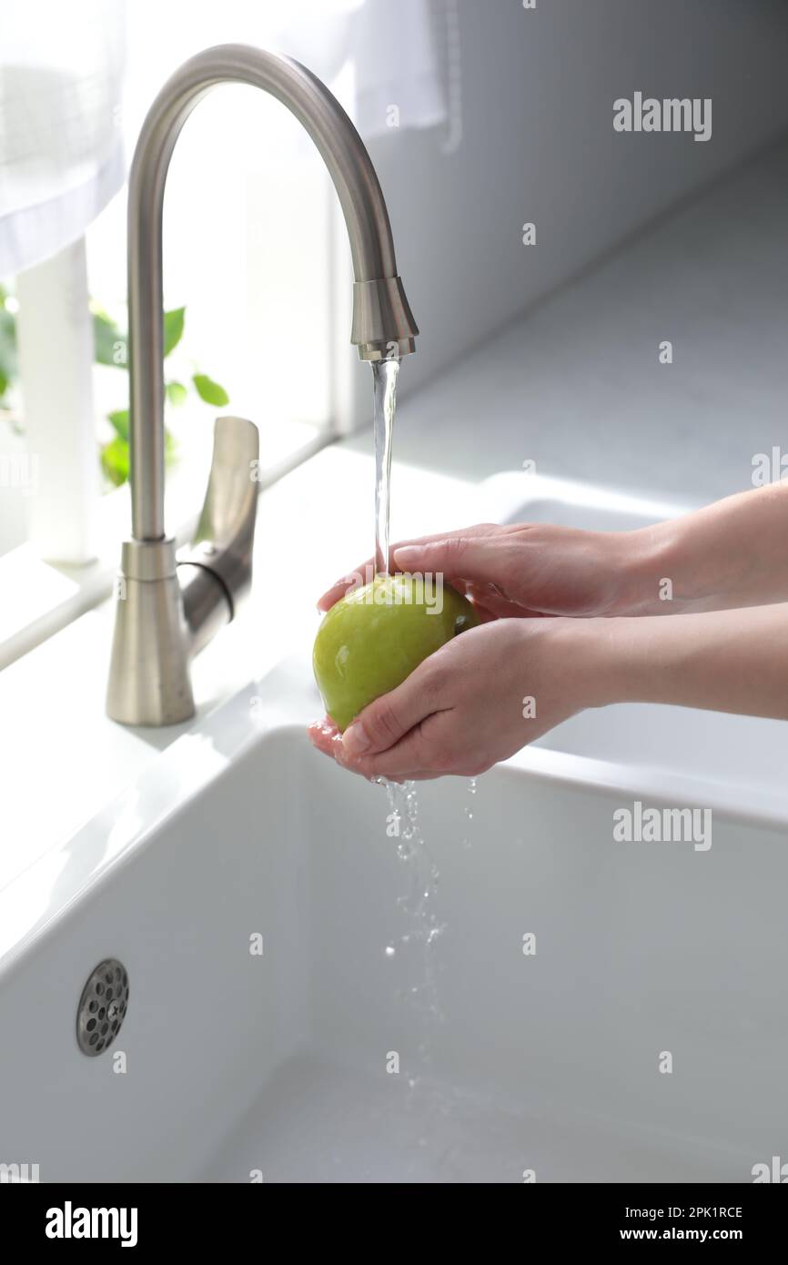 Femme lavant la pomme sur l'évier dans la cuisine, gros plan Banque D'Images