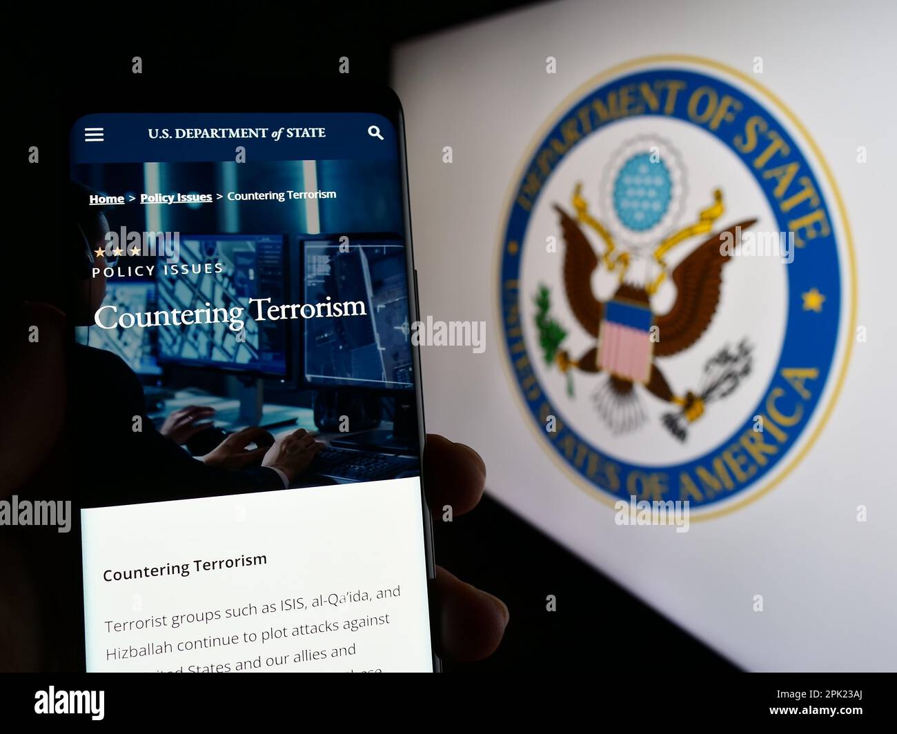 Personne tenant un smartphone avec une page Web du Département d'État des États-Unis (DOS) à l'écran devant le logo. Concentrez-vous sur le centre de l'écran du téléphone. Banque D'Images