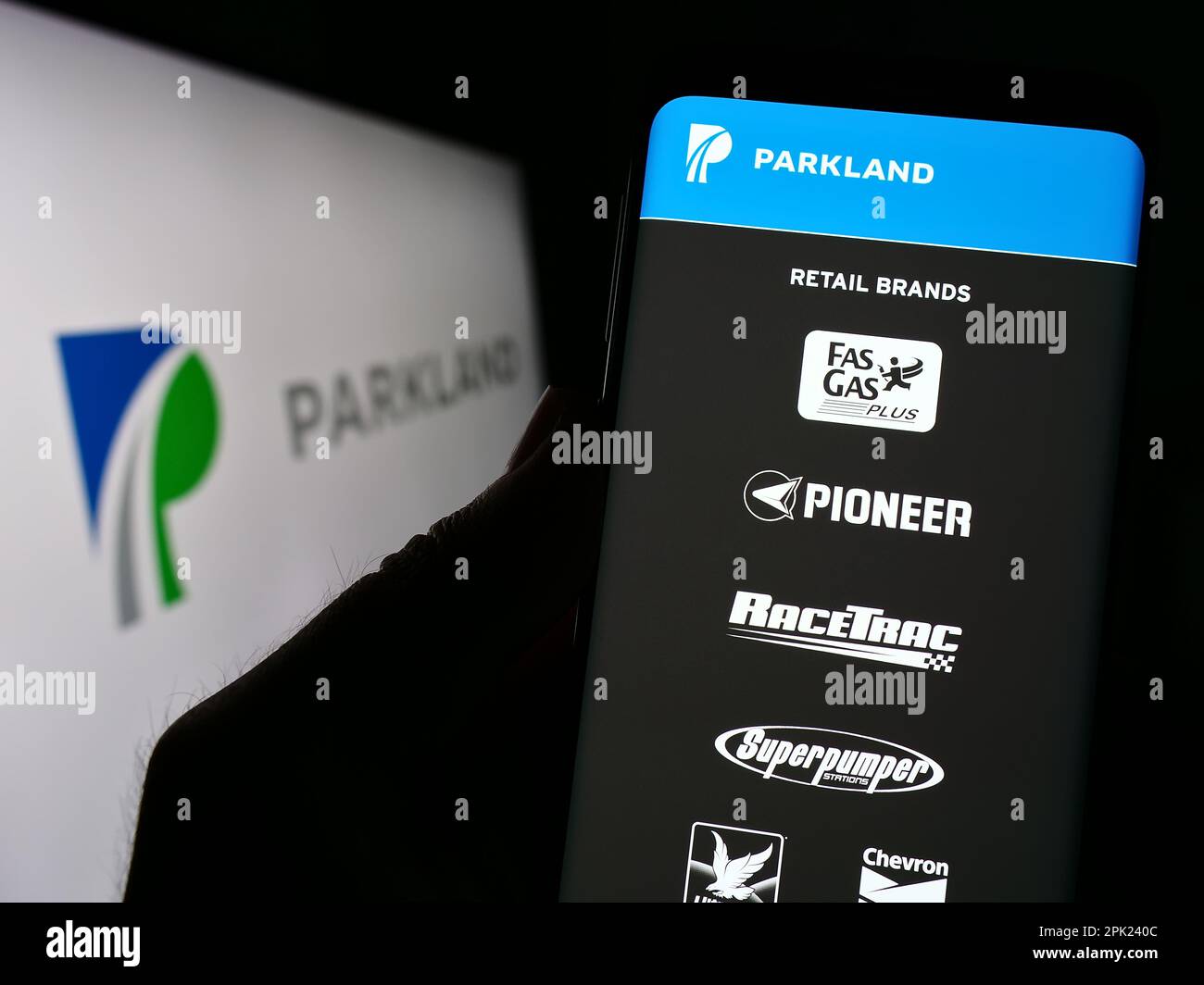 Personne tenant un téléphone cellulaire avec le site Web de la société de vente au détail d'énergie Parkland Corporation à l'écran devant le logo. Concentrez-vous sur le centre de l'écran du téléphone. Banque D'Images