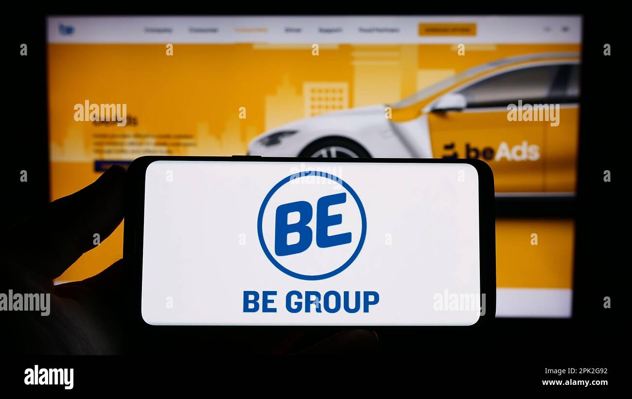 Personne tenant smartphone avec logo de la société vietnamienne de technologie être le Groupe JSC à l'écran en face du site Web. Mise au point sur l'affichage du téléphone. Banque D'Images