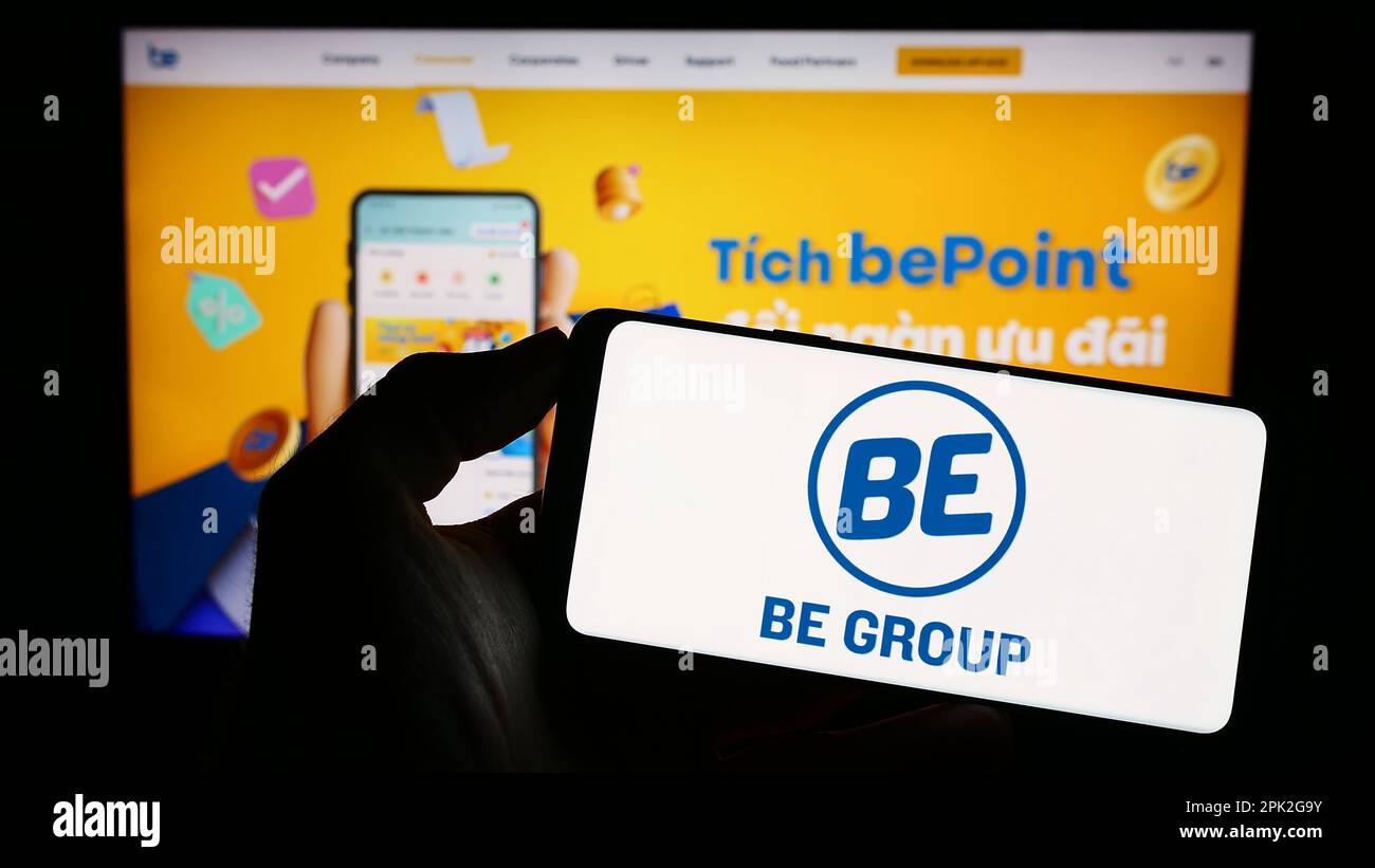 Personne tenant le téléphone mobile avec le logo de la société vietnamienne de technologie être Groupe JSC à l'écran en face de la page Web. Mise au point sur l'affichage du téléphone. Banque D'Images