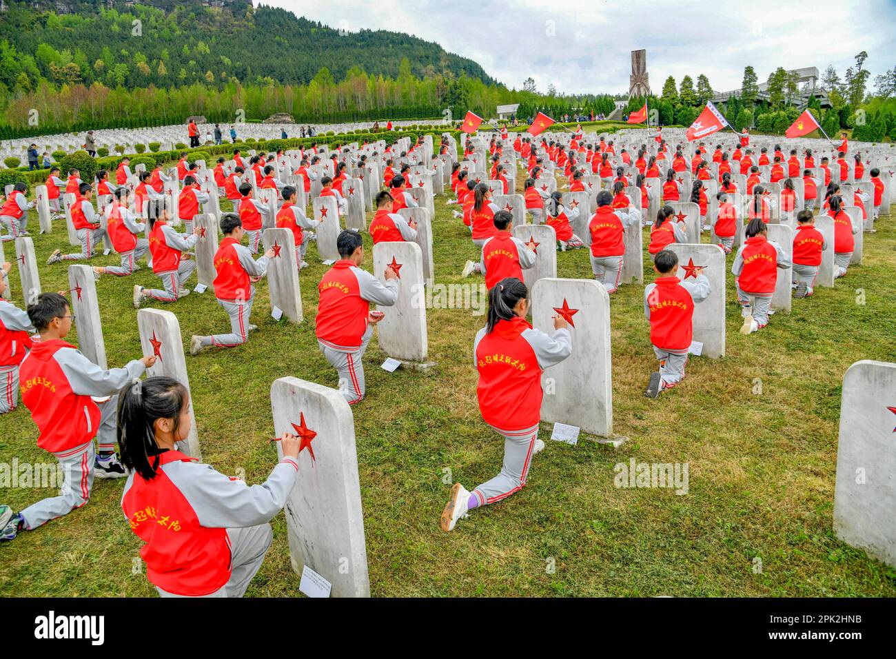 BAZHONG, CHINE - le 5 AVRIL 2023 - les élèves de l'école primaire peignent en rouge sur la pierre tombale d'un martyr inconnu au cimetière des martyrs de l'Armée rouge dans le sich Banque D'Images