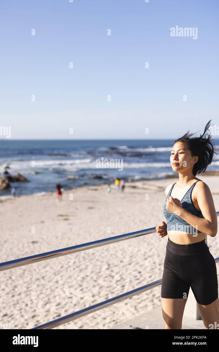 Bonne femme asiatique portant des vêtements de sport et courant sur la promenade au bord de la mer Banque D'Images