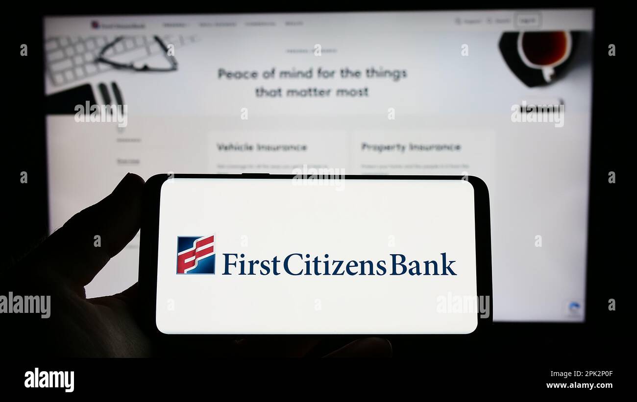 Personne tenant un smartphone avec le logo de la société financière américaine First Citizens Bank à l'écran devant le site Web. Mise au point sur l'affichage du téléphone. Banque D'Images