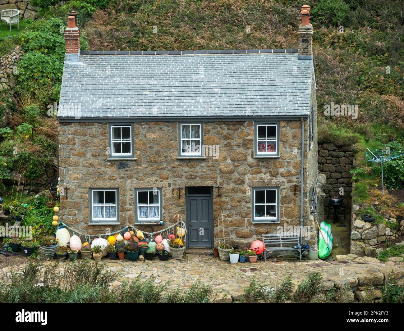 Beau vieux granit en pierre Cornouailles cottage bord de mer avec toit en ardoise et flotteurs de pêche et bouées à Penberth Cove, Cornwall, Royaume-Uni Banque D'Images