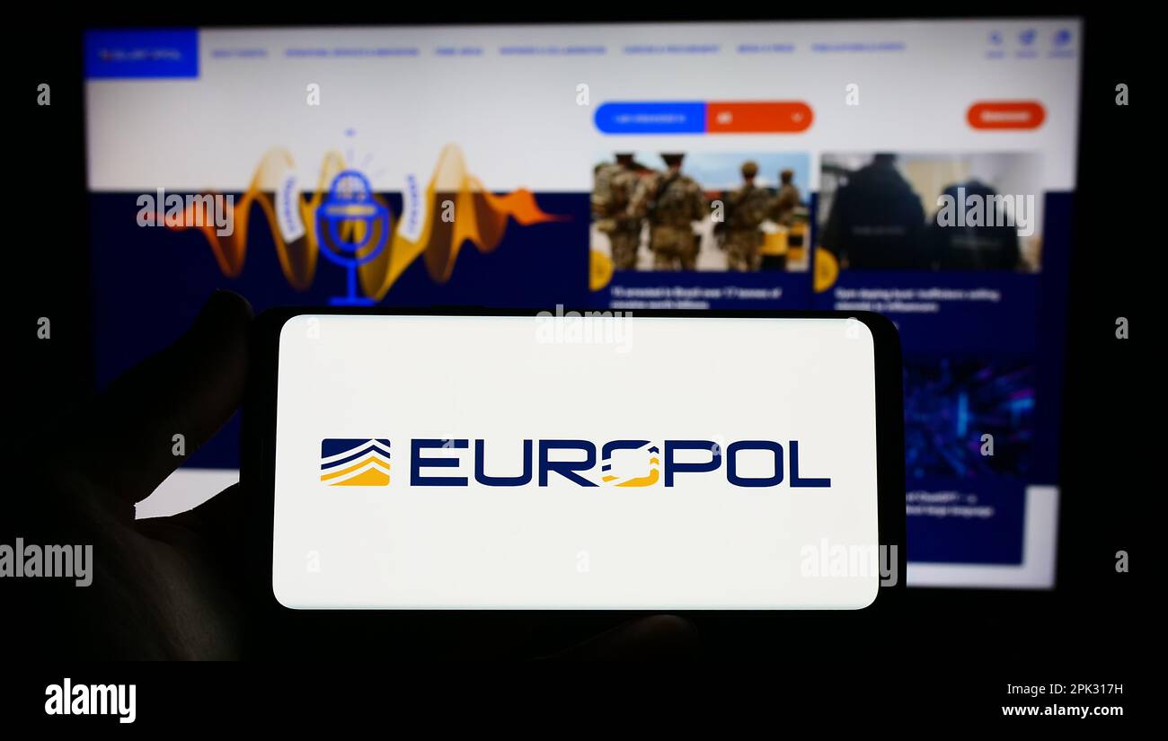 Titulaire d'un smartphone portant le logo de l'agence européenne chargée de l'application de la loi Europol à l'écran, devant le site Web. Mise au point sur l'affichage du téléphone. Banque D'Images