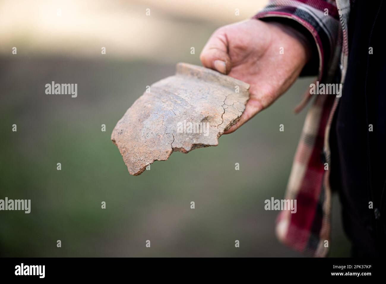 Lohe Rickelshof, Allemagne. 05th avril 2023. Un homme tient un morceau d'un pot en céramique estimé à ce jour de la 1-2 siècle AD. Les archéologues ont déjà découvert plus de 650 découvertes lors d'enquêtes sur le site d'une usine de batteries prévue à Lohe-Rickelshof (district de Dithmarschen). Credit: Daniel Reinhardt/dpa/Alay Live News Banque D'Images