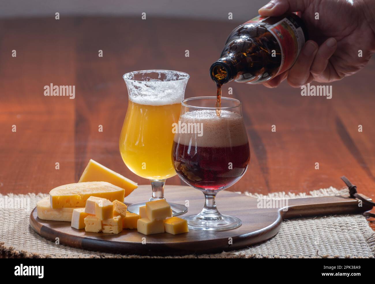 Verres de bière blonde jaune belge et brune foncée fabriqués en abbaye et en bois avec une variété de fromages belges, plats et bières assortis en Belgique Banque D'Images