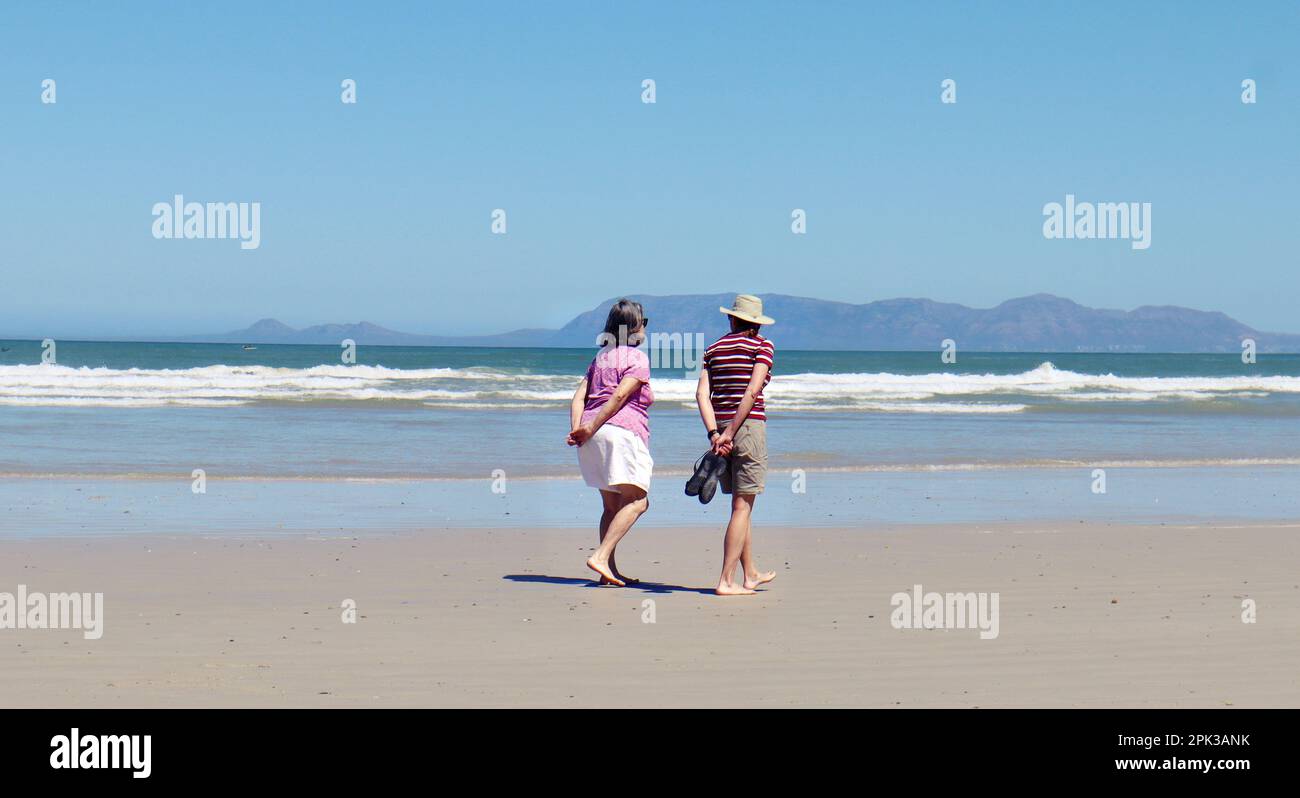 Vieux couple marchant sur la plage par une journée ensoleillée. Banque D'Images