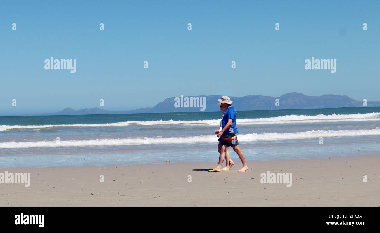 Vieux couple marchant sur la plage par une journée ensoleillée. Banque D'Images