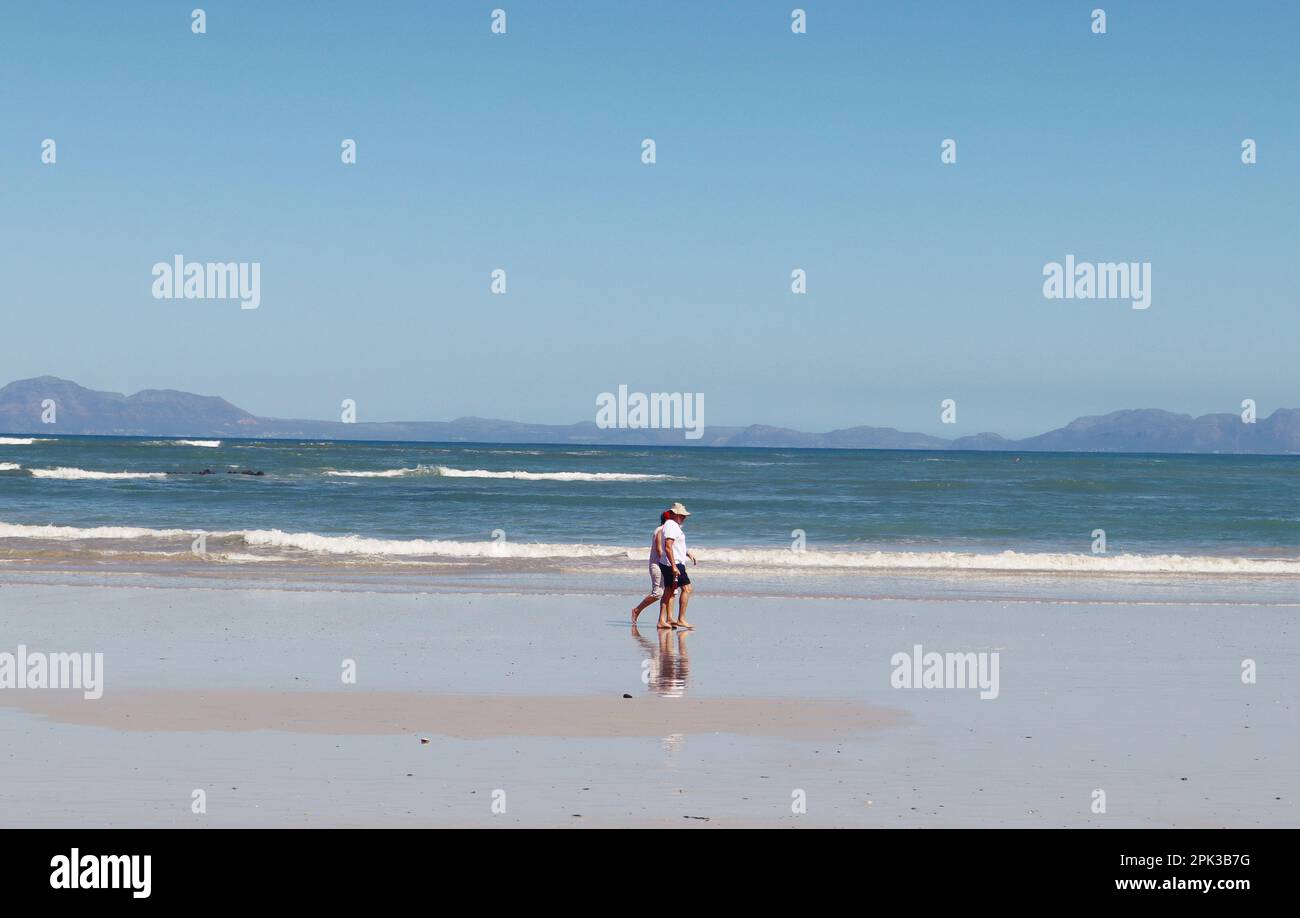 Vieux couple marchant sur la plage par une journée ensoleillée. Banque D'Images