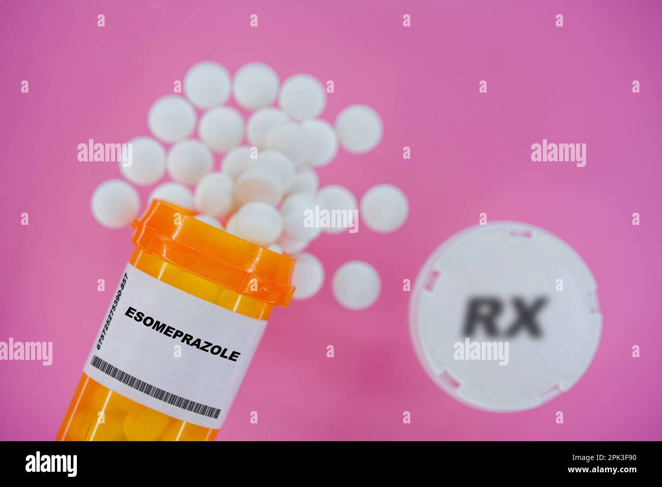 Esoméprazole Rx comprimés dans un flacon plactique avec comprimés. Les pilules débordent du contenant jaune sur fond rose. Banque D'Images
