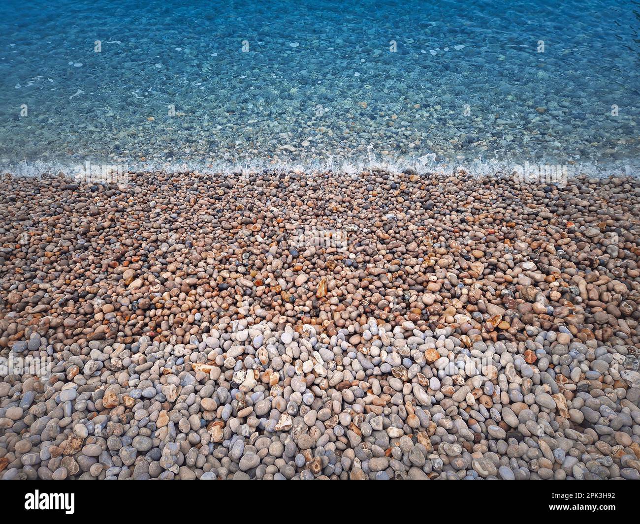 La plage de galets et la texture bleu de l'eau de mer Banque D'Images
