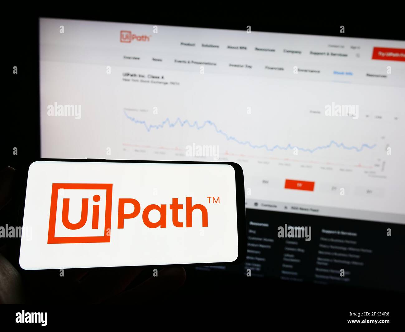 Personne tenant un téléphone mobile avec le logo de la société de logiciel d'automatisation UiPath Inc. Sur l'écran en face de la page Web d'affaires. Mise au point sur l'affichage du téléphone. Banque D'Images
