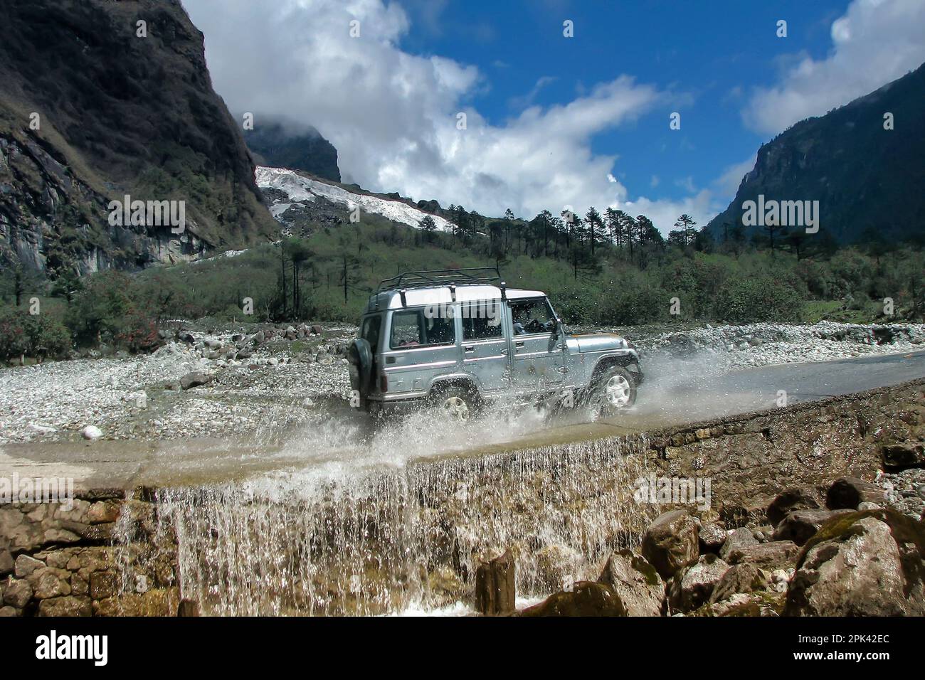 Voiture touristique traversant la fontaine à Yumthang Valley ou Sikkim Valley of Flowers sanctuaire, montagnes de l'Himalaya, Sikkim Nord, Inde. Shingba Rhododendron Banque D'Images