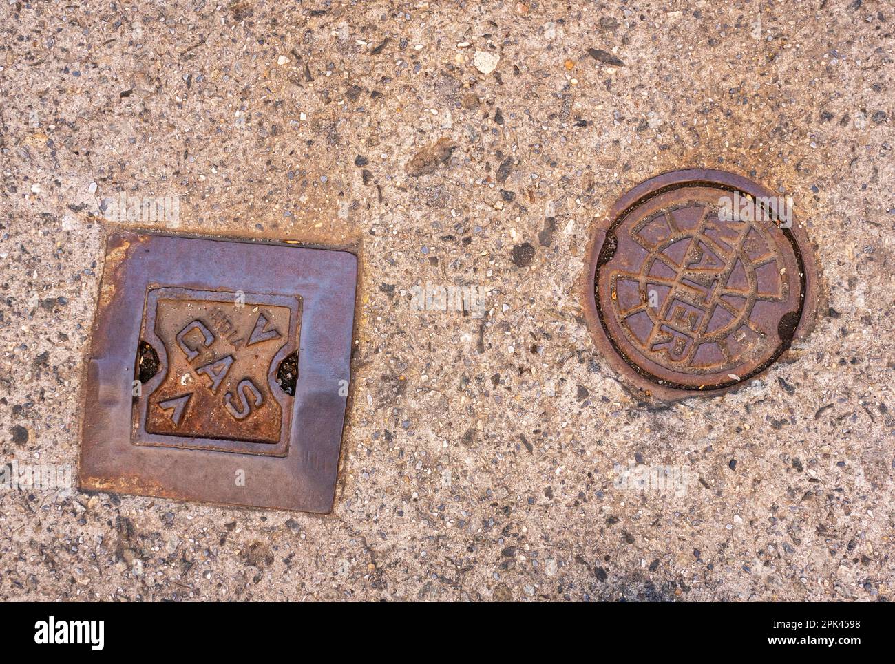 Les couvercles des vannes d'arrêt pour le gaz naturel et l'eau sont encastrés dans le trottoir de Chelsea, à New York, dimanche. 2 avril 2023. New York a proposé une interdiction des raccordements de gaz dans les nouvelles constructions. (© Richard B. Levine) Banque D'Images