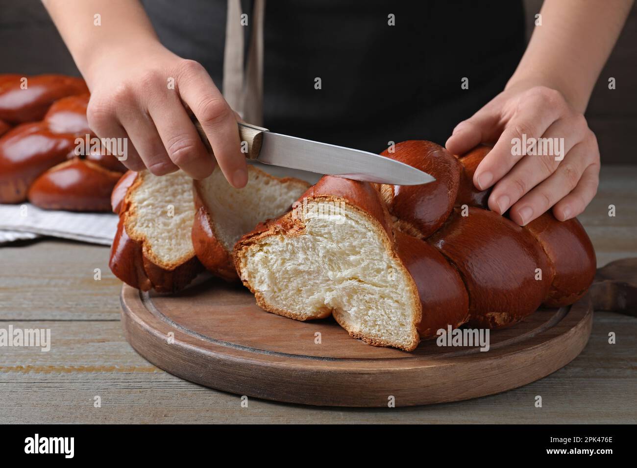 Femme coupant du pain tressé fait maison à une table en bois, gros plan. Challah pour Shabbat Banque D'Images