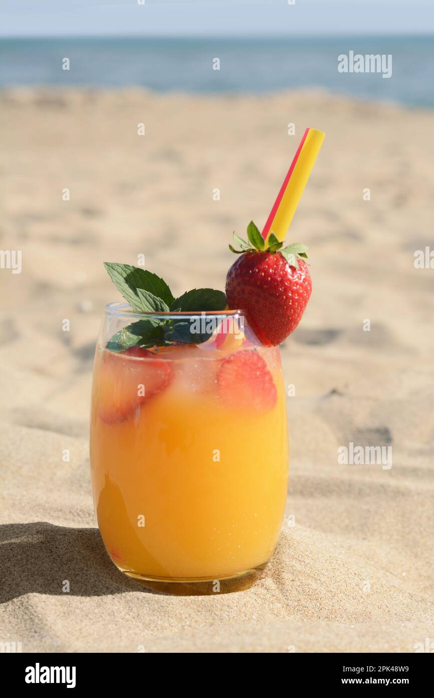 Verre de boisson rafraîchissante avec fraise sur la plage de sable près de la mer Banque D'Images