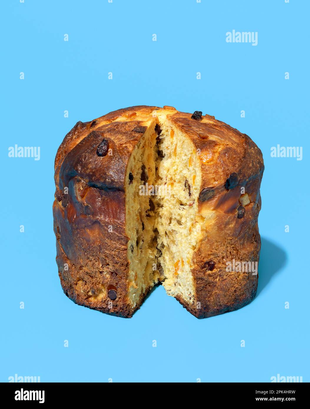 Tons panettone tranchés dans une lumière vive minimaliste sur une table bleue. Délicieux panettone de levain maison avec raisins secs, zeste d'orange confite et chocolat Banque D'Images