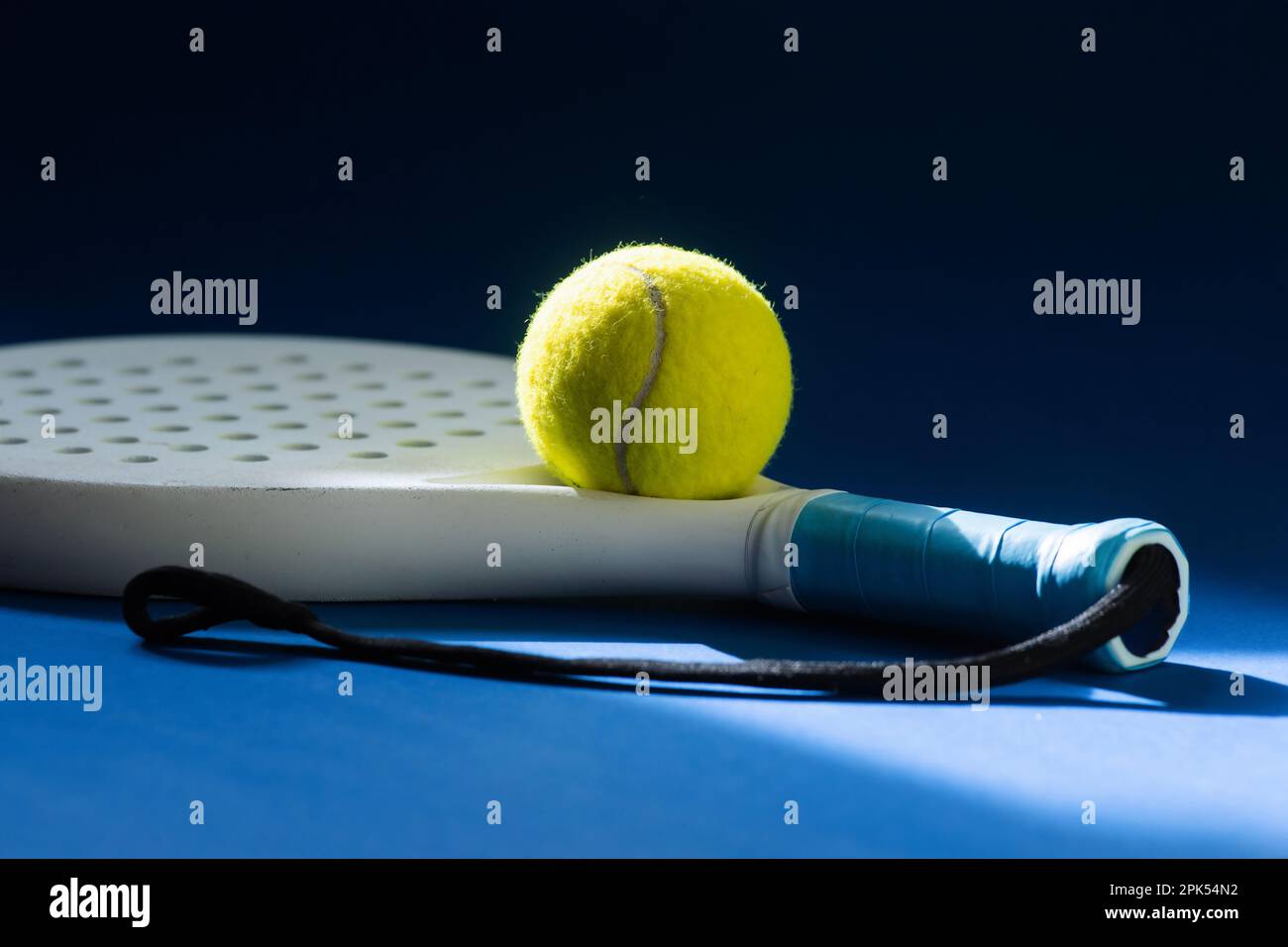 Raquette de paddle-tennis professionnelle blanche et balle jaune avec éclairage naturel sur fond bleu. Affiche horizontale sur le thème du sport, cartes de vœux, tête Banque D'Images